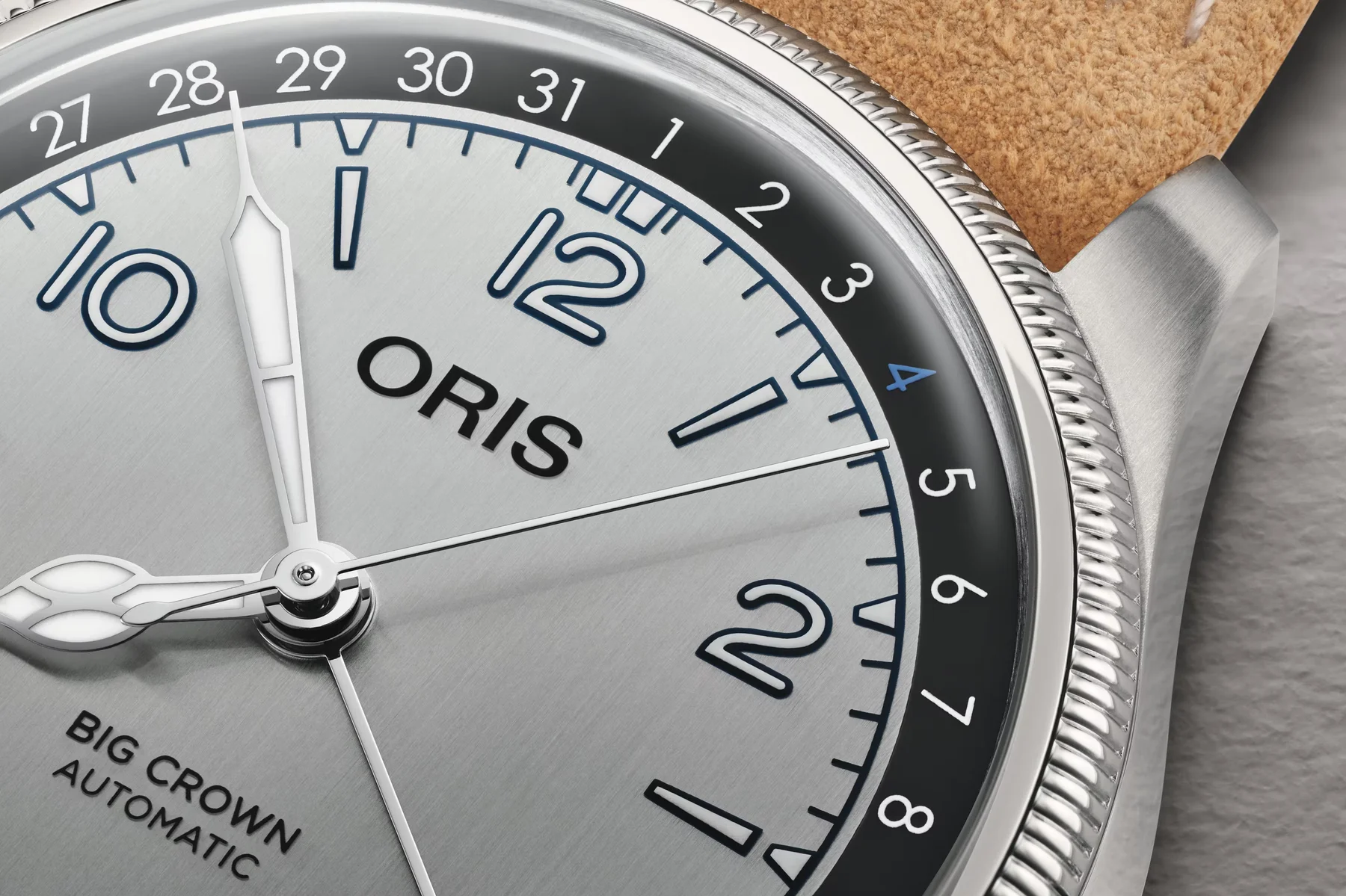 Close-up of Oris Big Crown Automatic watch. Silver dial, blue numerals, white hands, fluted bezel, brown suede strap.