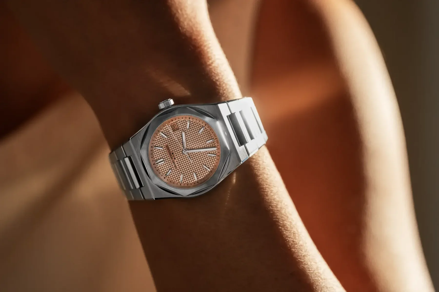Girard-Perregaux watch with rose gold textured dial and steel integrated bracelet on a wrist.