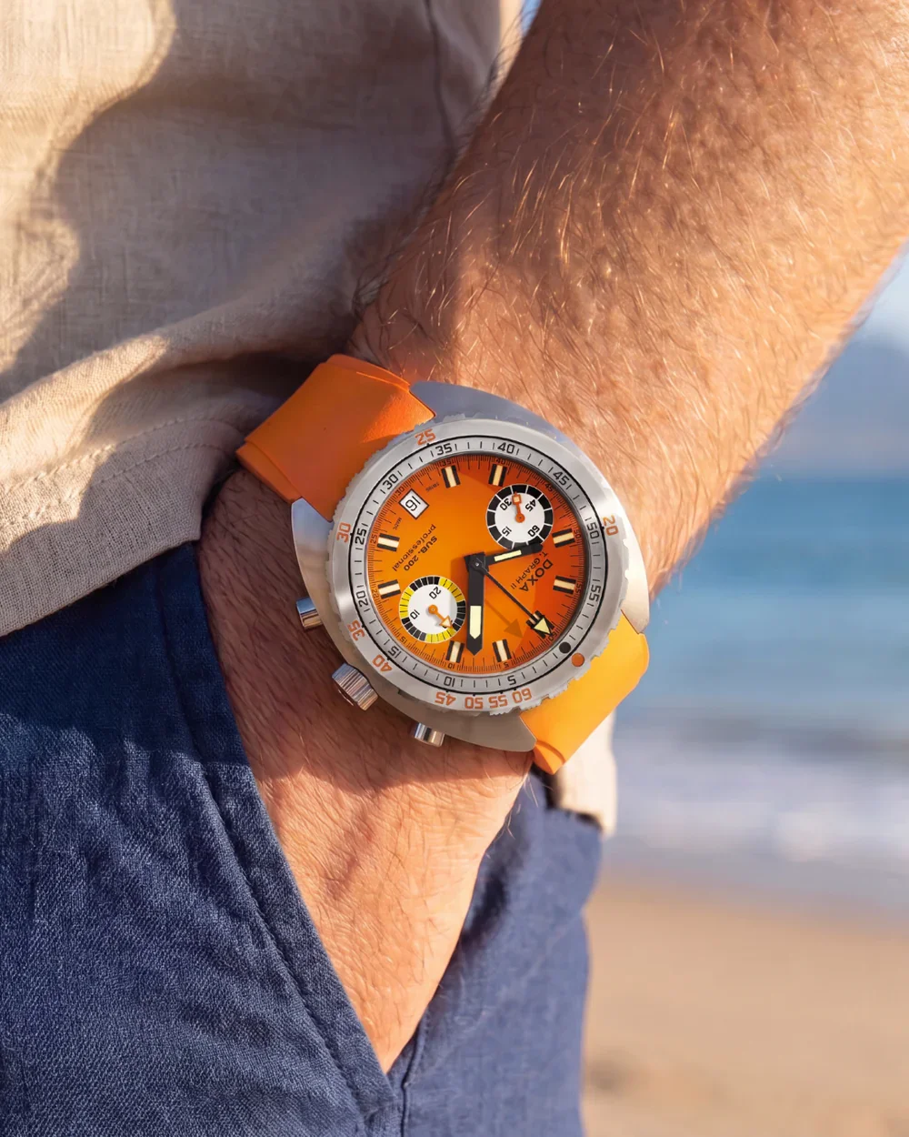 DOXA SUB 200 T.Graph II Professional with orange dial & strap on man's wrist at the beach.