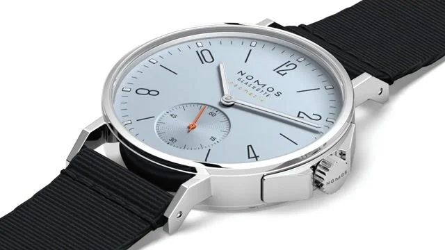 Nomos Glashütte Ahoi Neomatik 36 Sky watch: light blue dial, silver case, black fabric strap, orange sub-seconds hand, white background.
