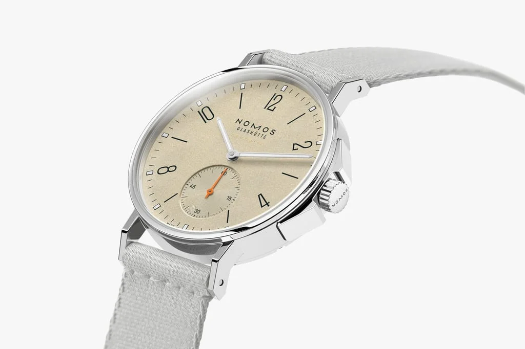 Nomos Ahoi Neomatik 36 Sand watch, angled view. Beige textured dial, silver case, light grey textile strap, orange sub-seconds.