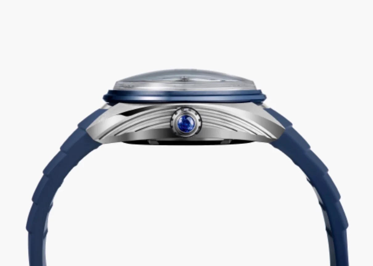 Side view of a Seiko watch: blue rubber strap, grooved silver case, blue crown jewel, and domed crystal.