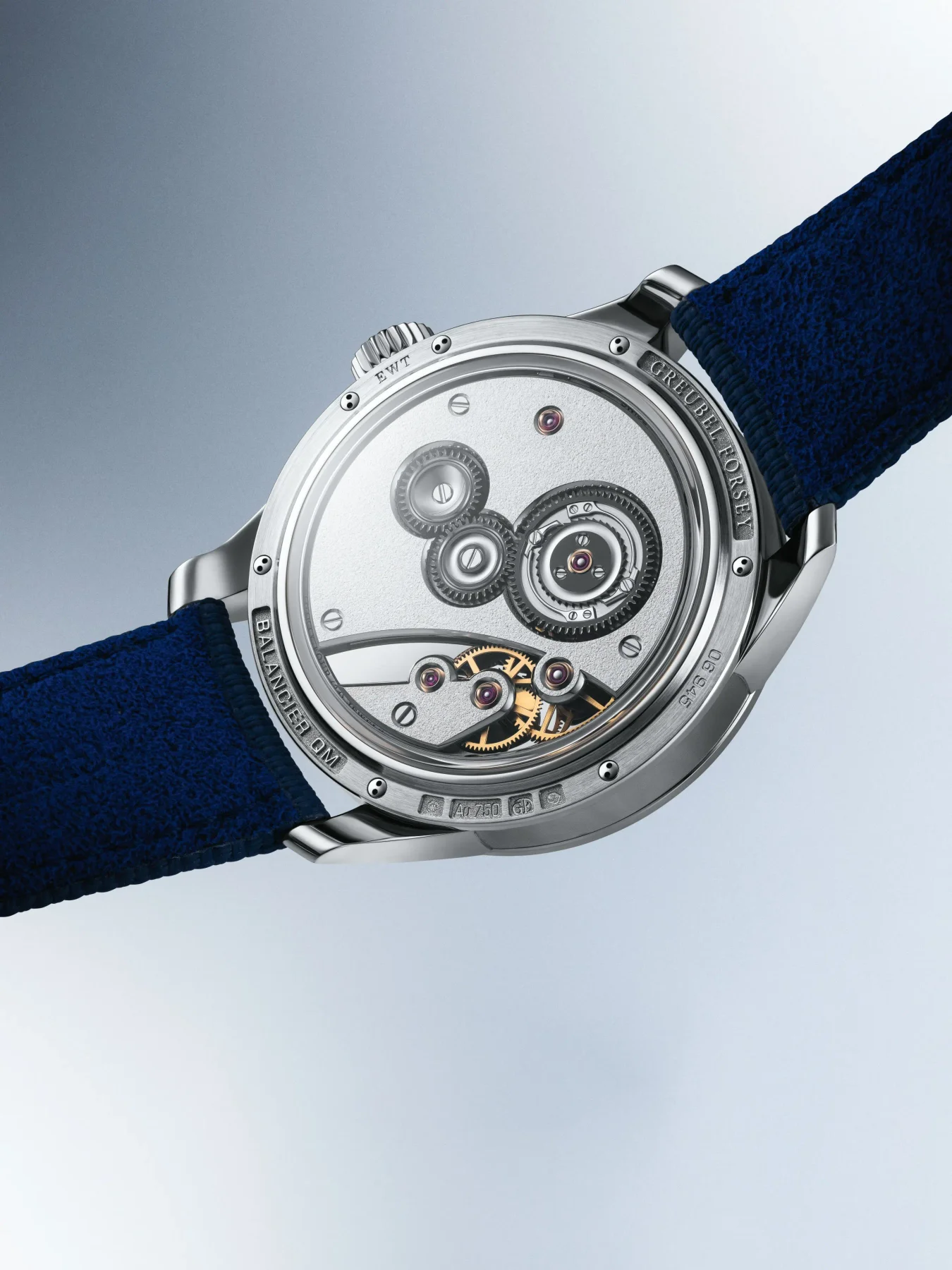 Greubel Forsey Balancier DM white gold watch back, revealing intricate mechanical movement with gears, rubies, and a blue strap.