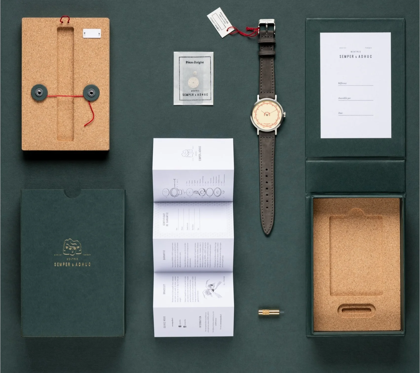 Semper & Adhuc watch (cream dial, grey strap) with elegant cork packaging, documents, and gold tool on dark green.