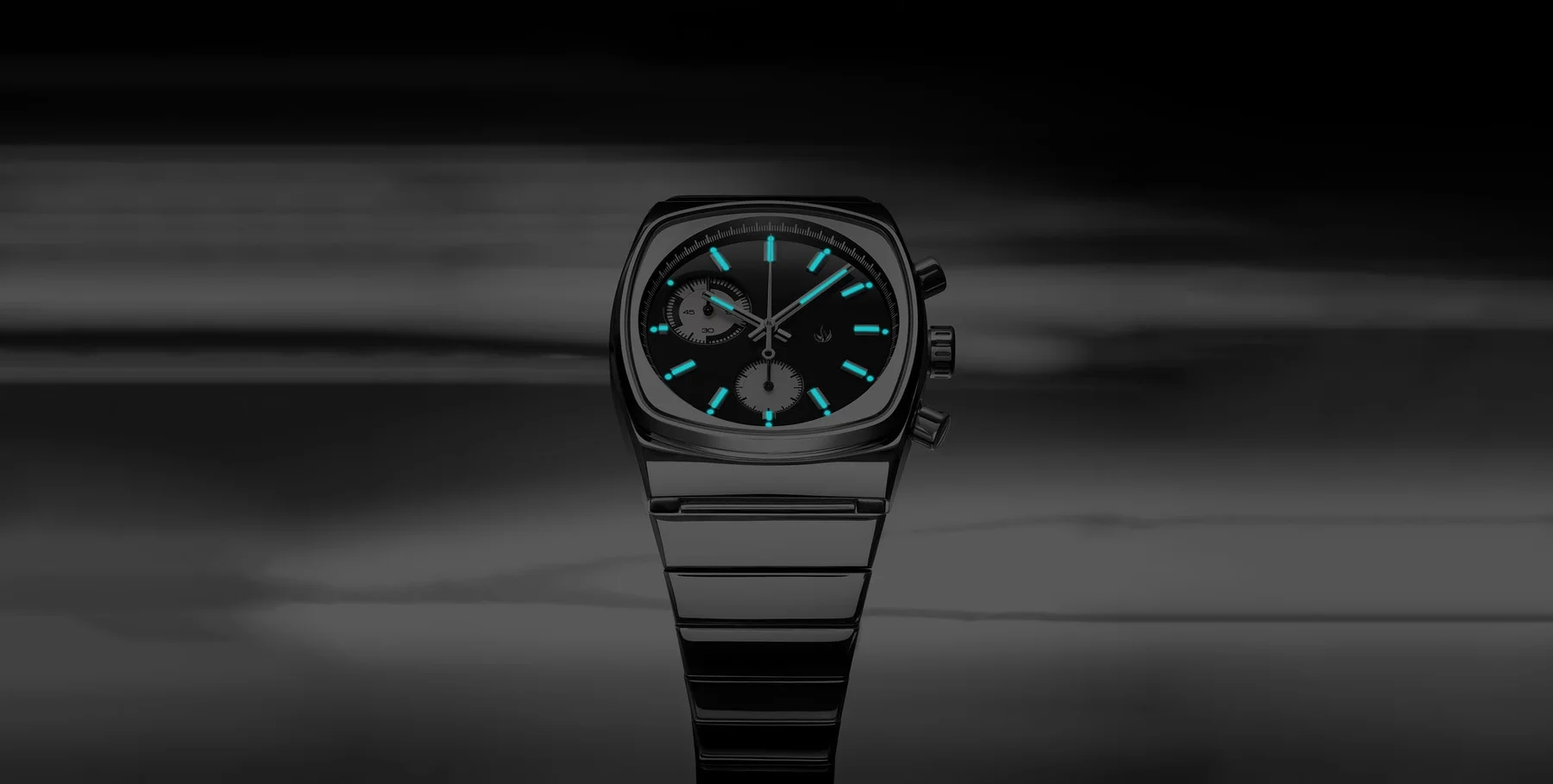 Cushion-cased chronograph watch with glowing blue hands & markers on a black dial, polished metal bracelet, dark reflective setting.