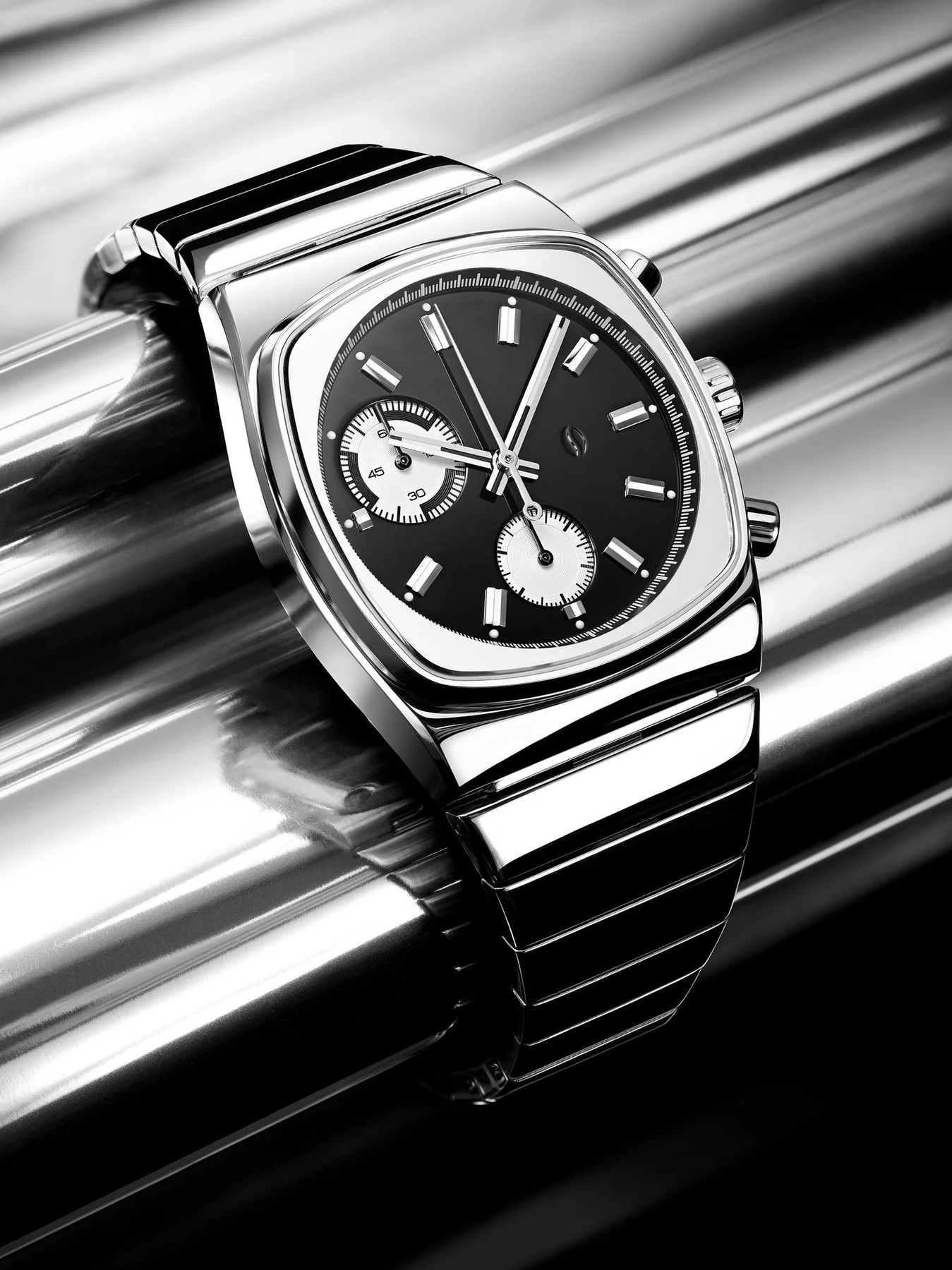 Monochrome luxury watch with steel square case, black dial, white sub-dials, and integrated bracelet on ribbed metal.