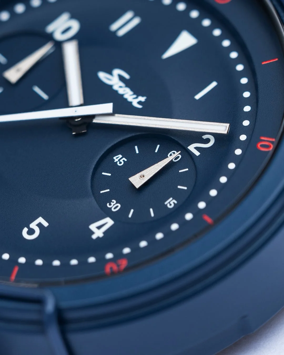 Close-up of a Moonstone Blue Scout watch dial with white hands, numbers, red accents, and a seconds sub-dial.