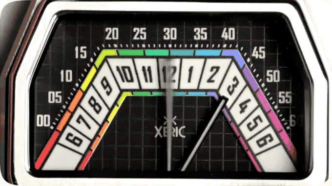 Xeric watch face with black grid, colorful hour/minute tracks, and hands indicating approx. 12:17.