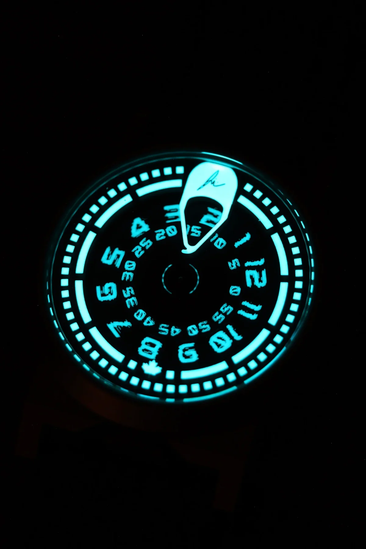 Luminous aqua blue watch face in darkness, displaying hours, minutes, and a stylized, glowing hour indicator.