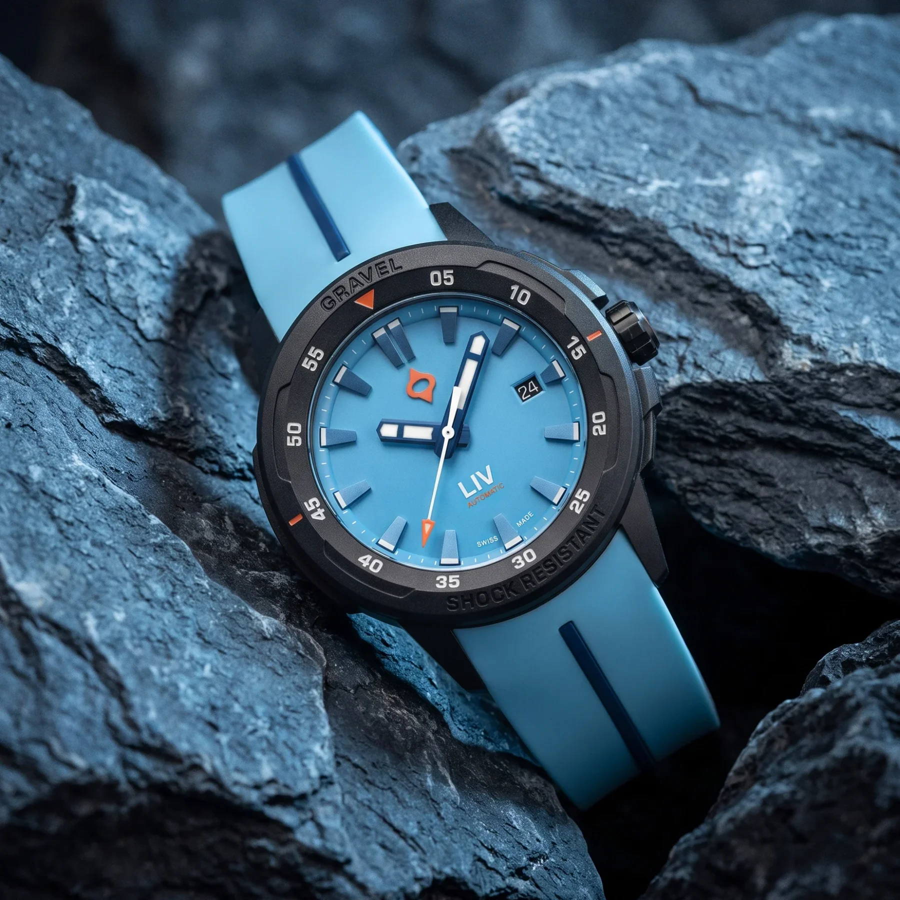 Light blue LIV Gravel watch with black bezel, orange accents, blue rubber strap, on dark gray rocks.