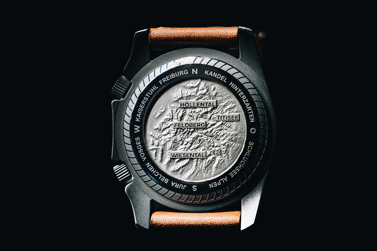 Luxury watch case back features a detailed topographic map of Feldberg & Titisee with surrounding regional names. Brown strap.