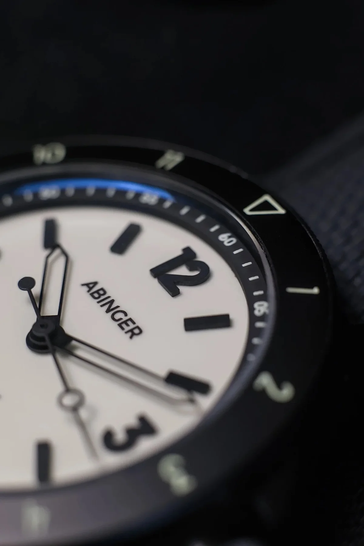 Close-up: Abinger watch, cream dial, black hands & '12', black bezel with blue arc & white markers.