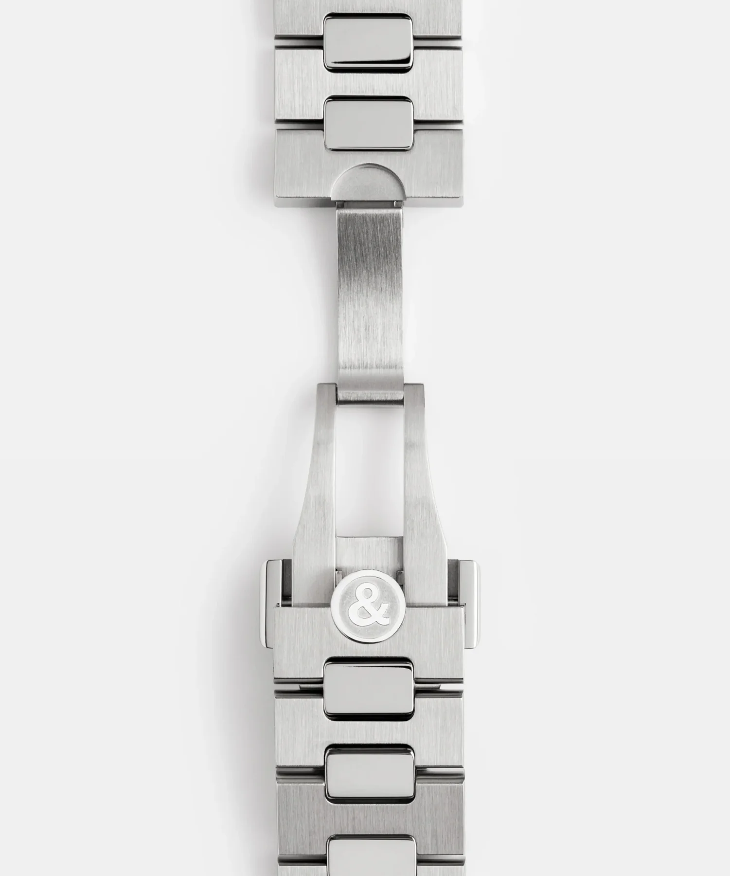 Brushed steel luxury watch bracelet with an integrated butterfly clasp and ampersand logo on white.