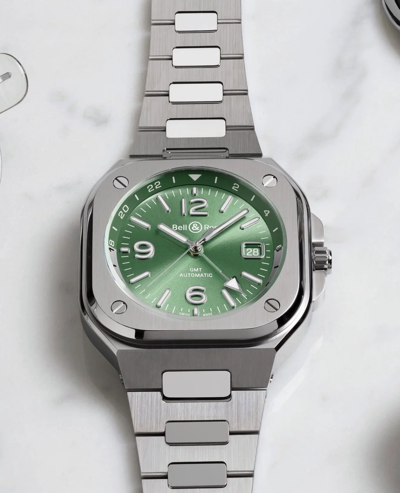 Bell & Ross BR-05 GMT watch with green dial, square steel case, integrated steel bracelet on marble.