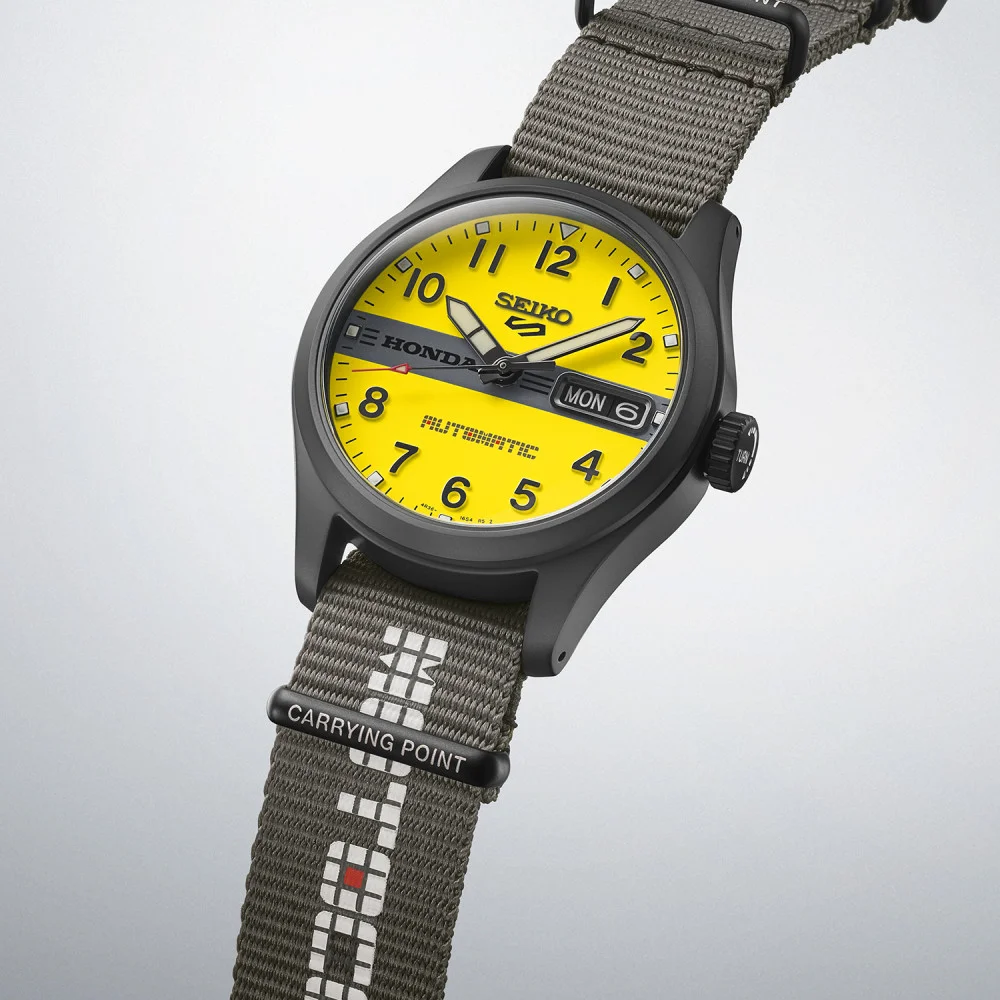 Seiko Honda watch with black case, bright yellow dial, black stripe, MON 6. Black nylon strap with Carrying Point.