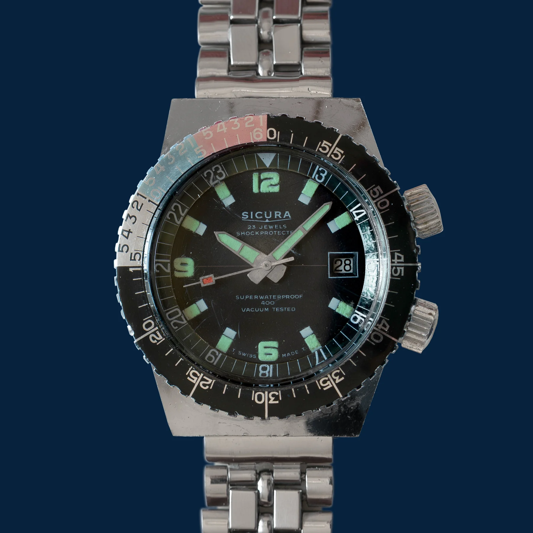 Vintage Sicura diver's watch with black dial, green hands & markers, date 28, two crowns, steel bracelet.