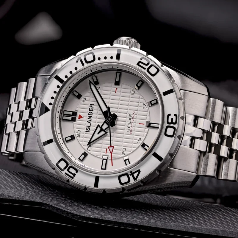 Close-up of silver Islander solar diver watch. White textured dial, white diving bezel with black numerals, steel jubilee bracelet.