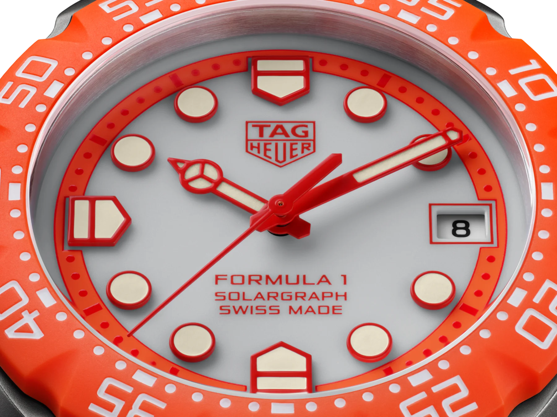 Close-up of TAG Heuer Formula 1 Solargraph watch: orange bezel, white dial, red hands, luminous markers, date '8'.