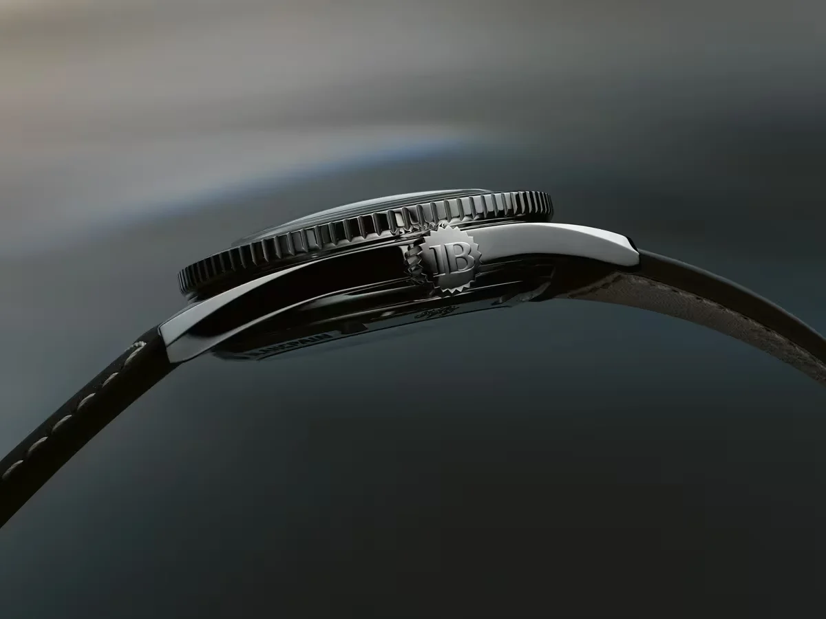Side view of a Blancpain watch. Polished case, knurled bezel, JB crown, and dark leather strap with white stitching.