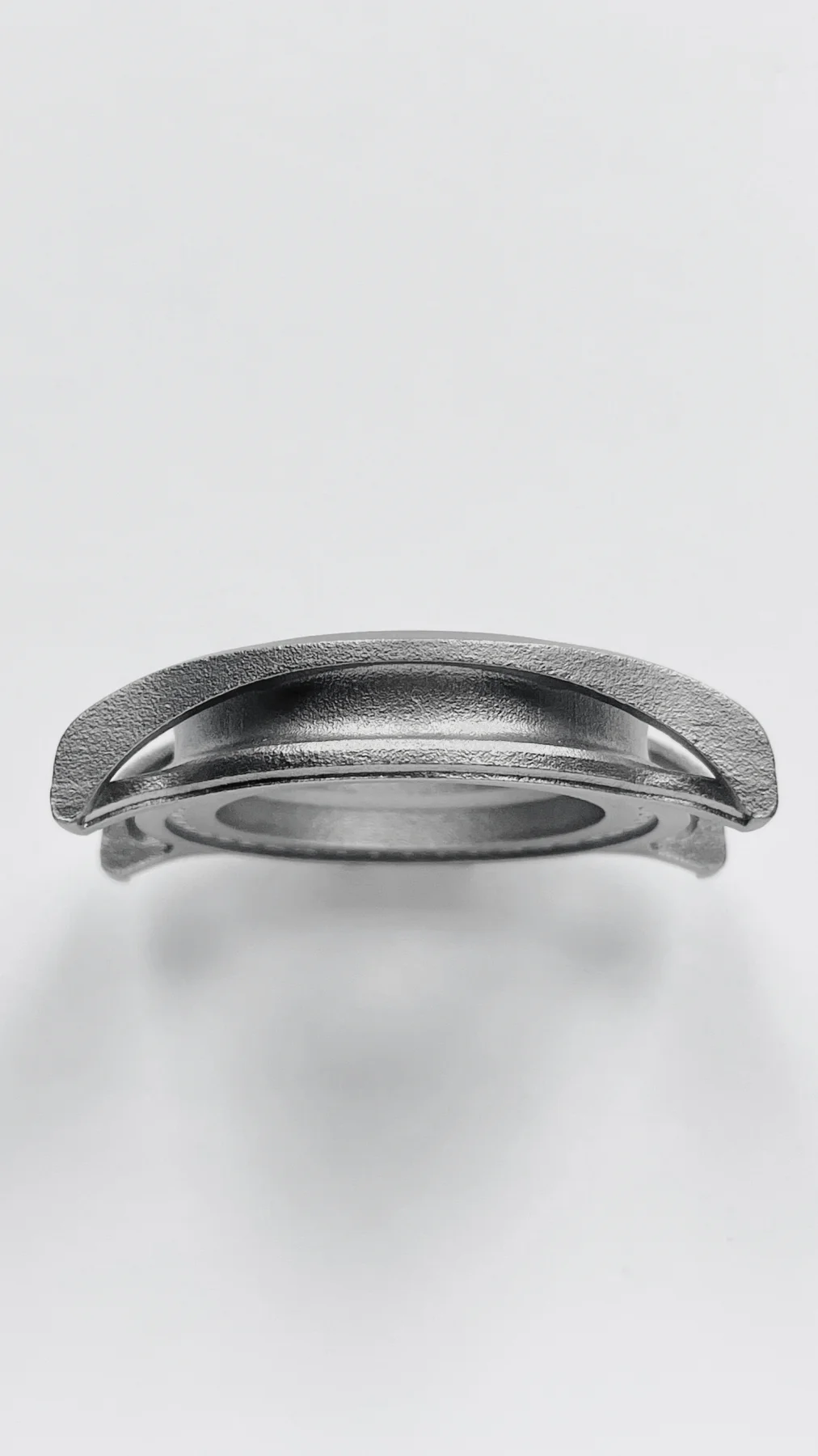Side profile of a textured gray metal watch case with granular finish, on a white background.