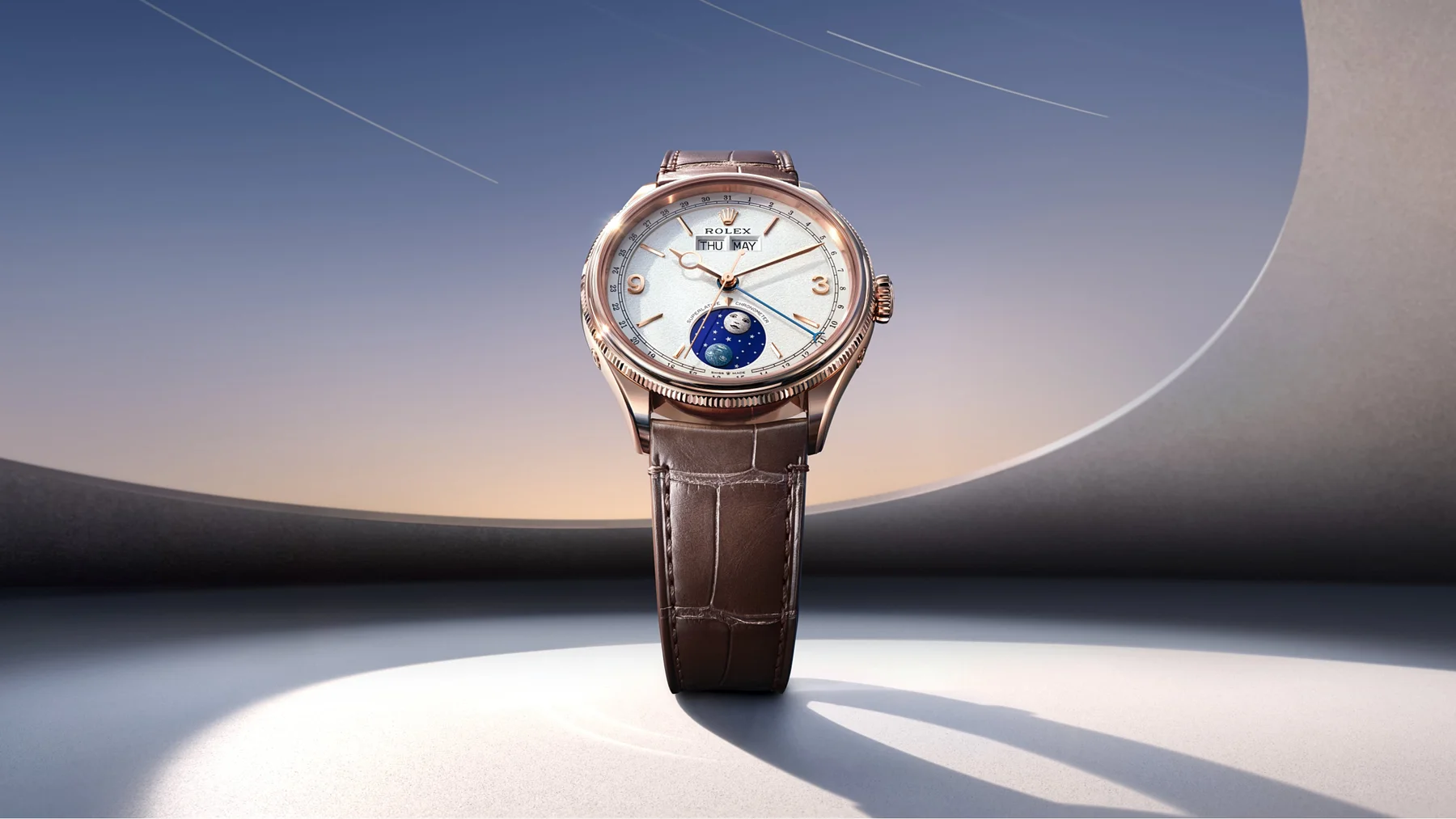 Rose gold Rolex Cellini Moonphase, white dial, brown alligator strap, day/month/moon phase complications. Abstract setting.