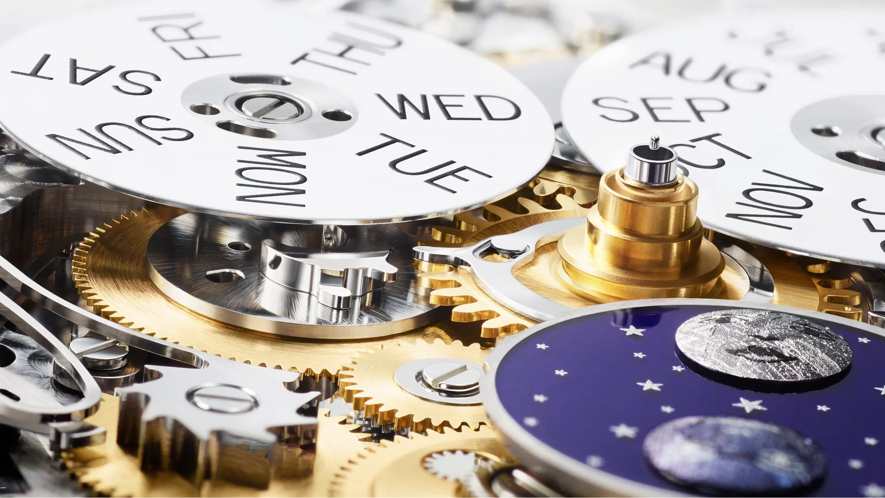 Detailed view of luxury watch movement: day/month discs, brass & silver gears, and a blue moon phase display.