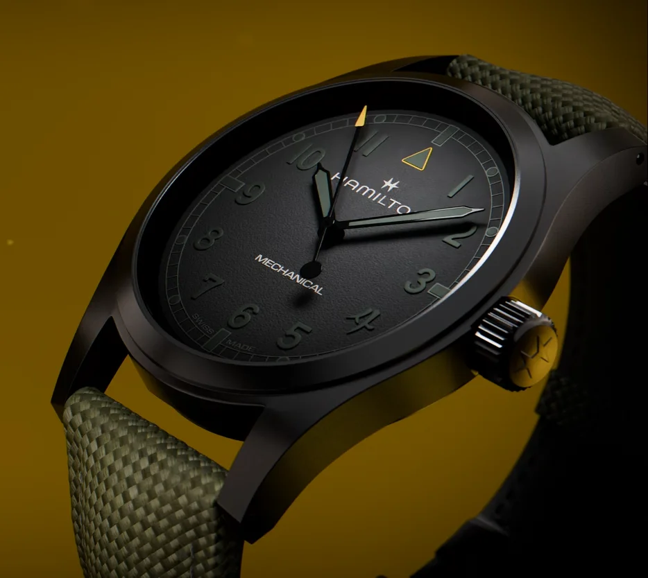 Matte black Hamilton Mechanical watch with dark green dial details, olive woven strap, yellow crown and background.
