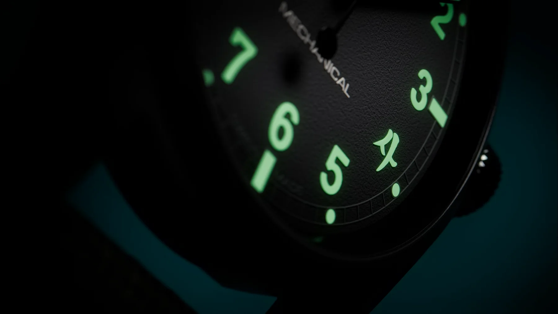 Angled close-up of a dark watch dial. Green luminous numerals, a stylized '4' symbol, and 