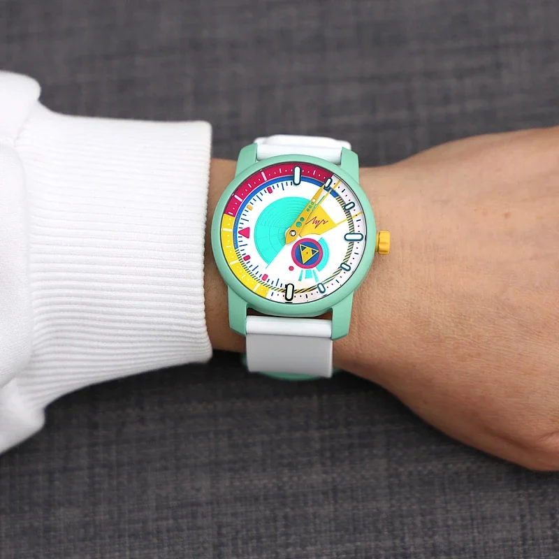 Person's wrist wears a mint green watch with white strap. Its colorful, abstract dial has a prominent turquoise circle.