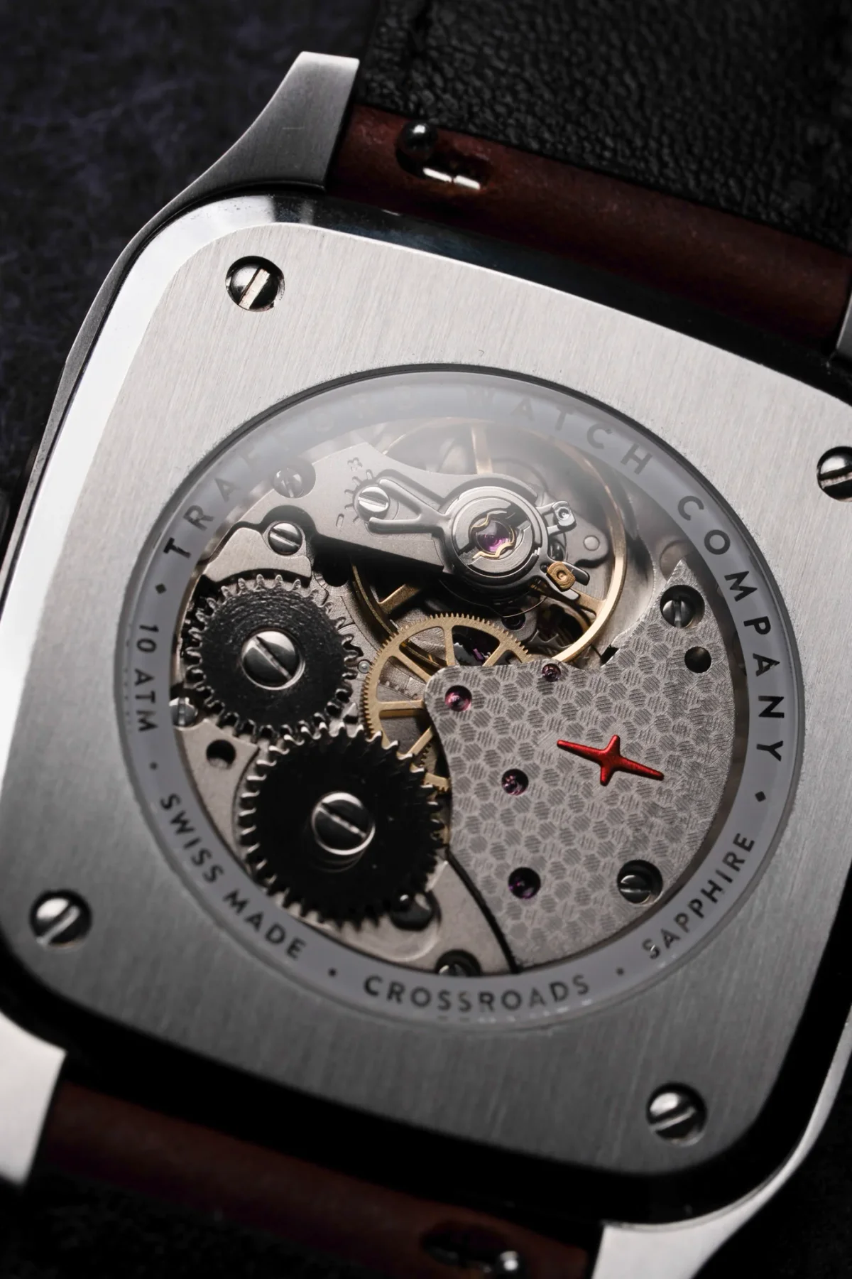 Square TRAIL Watch Company case back showing automatic movement, gears, jewels, red star. Brushed steel & brown strap.