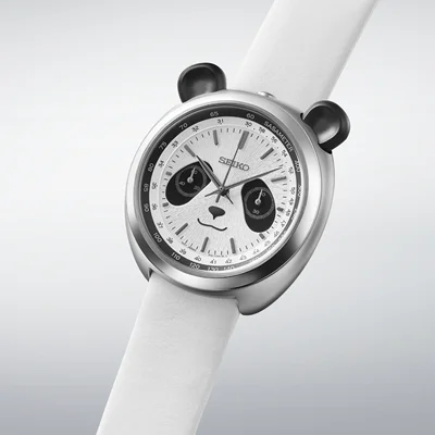 Seiko panda-dial chronograph watch with black subdials and ear-like pushers, on a white strap, studio shot.