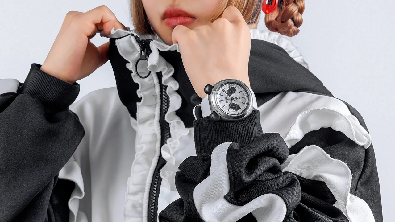 Person in black & white outfit wears Seiko panda chronograph watch with white strap, black pushers & panda face dial.