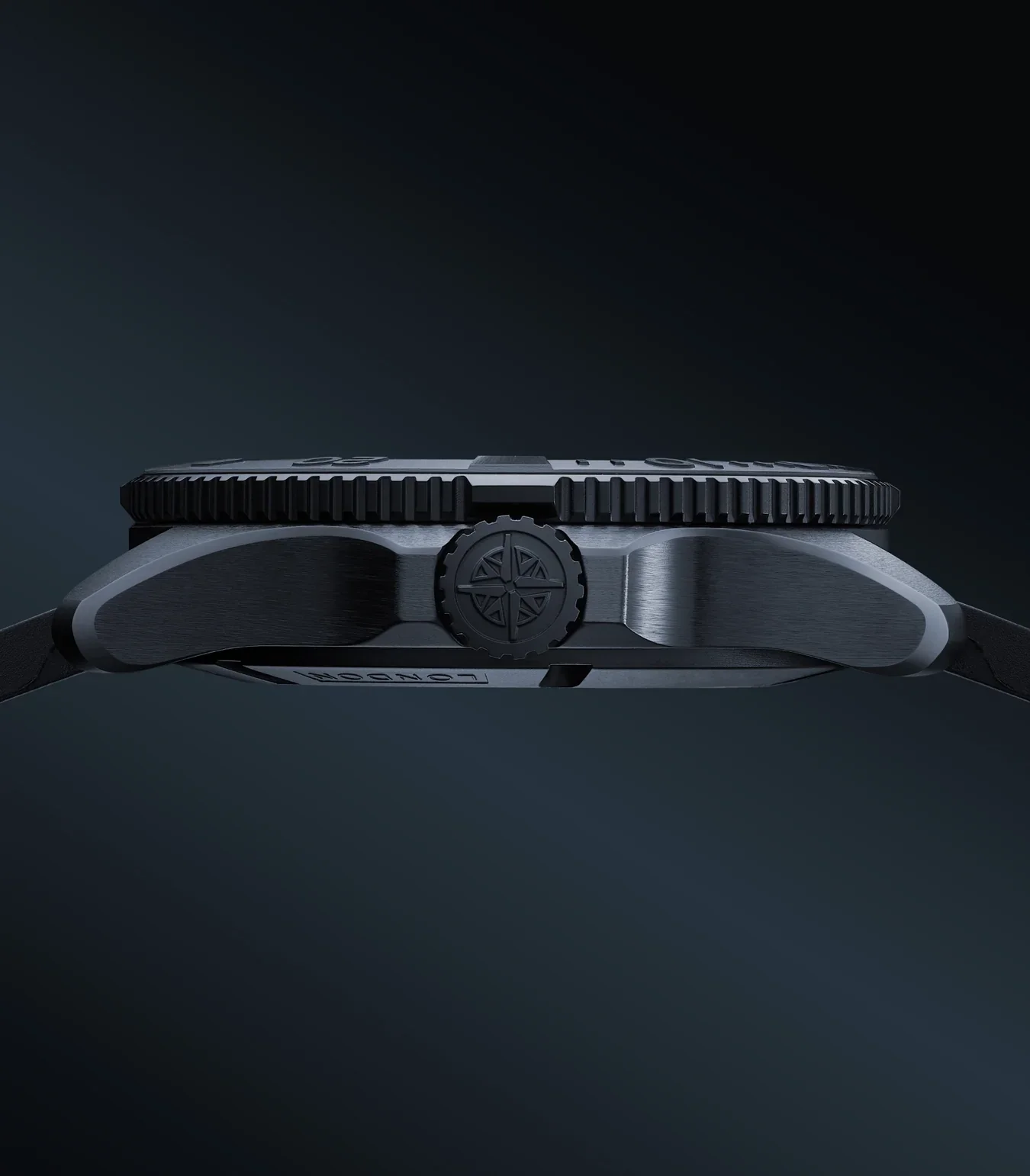 Side profile of a dark grey dive watch. Knurled bezel, compass rose crown, brushed case, black strap, 'LONDON' text.