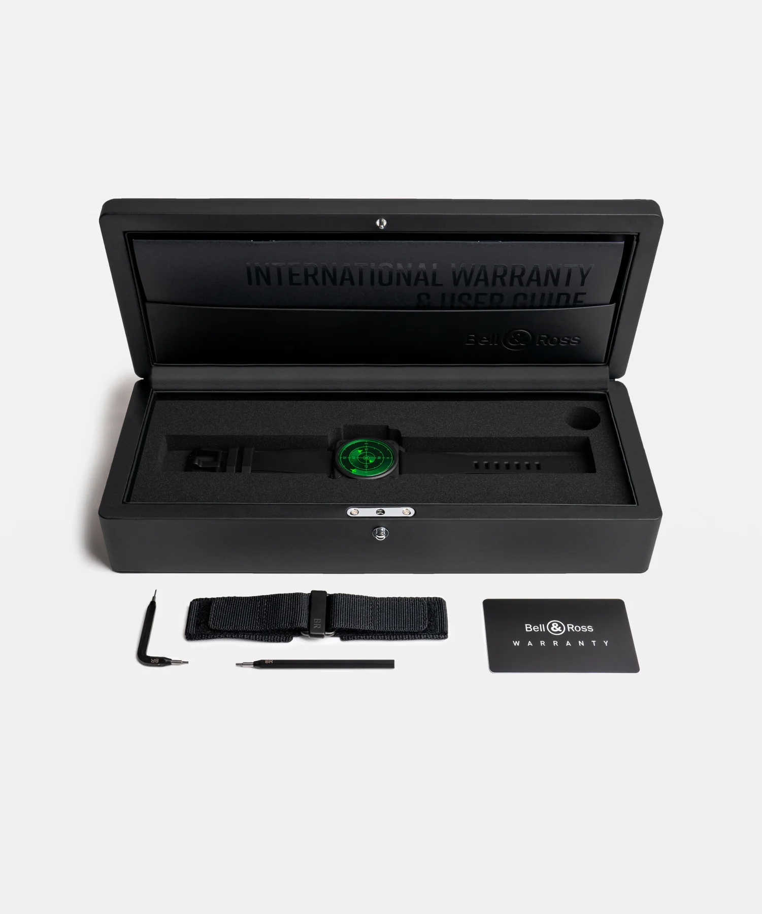 Bell & Ross watch with green radar dial in open box with "International Warranty" text. Extra strap, tools, card.