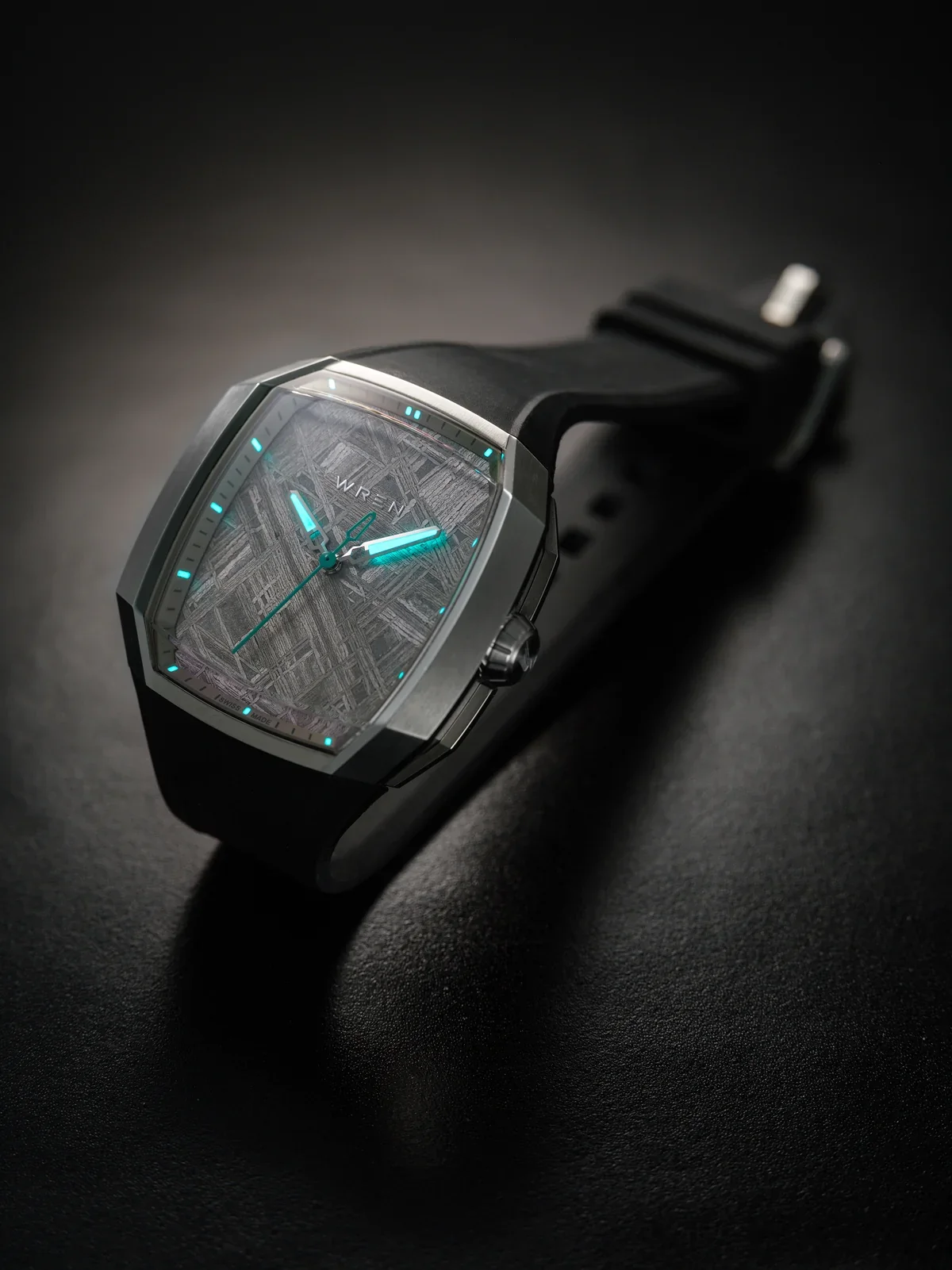 WREN integrated sports watch: angular grey case, meteorite dial, glowing teal hands/markers, black rubber strap on dark surface.