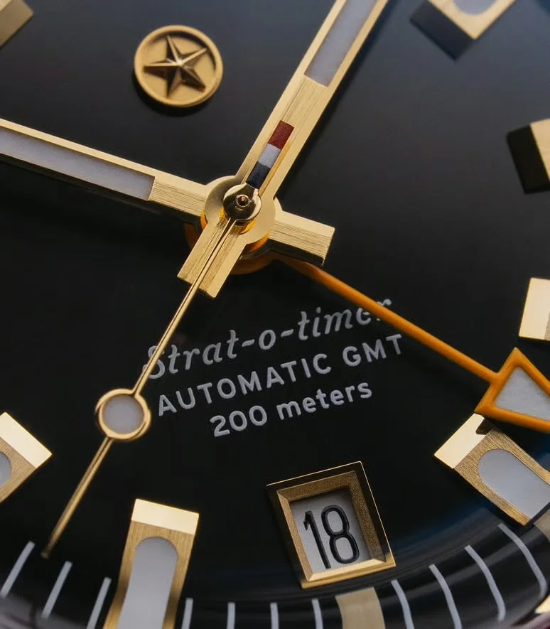 Close-up of black watch dial. Gold hands, luminous markers, date