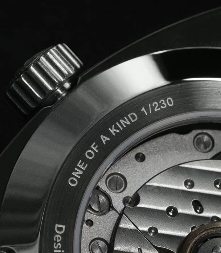Close-up of a watch showing its fluted crown, engraved case back