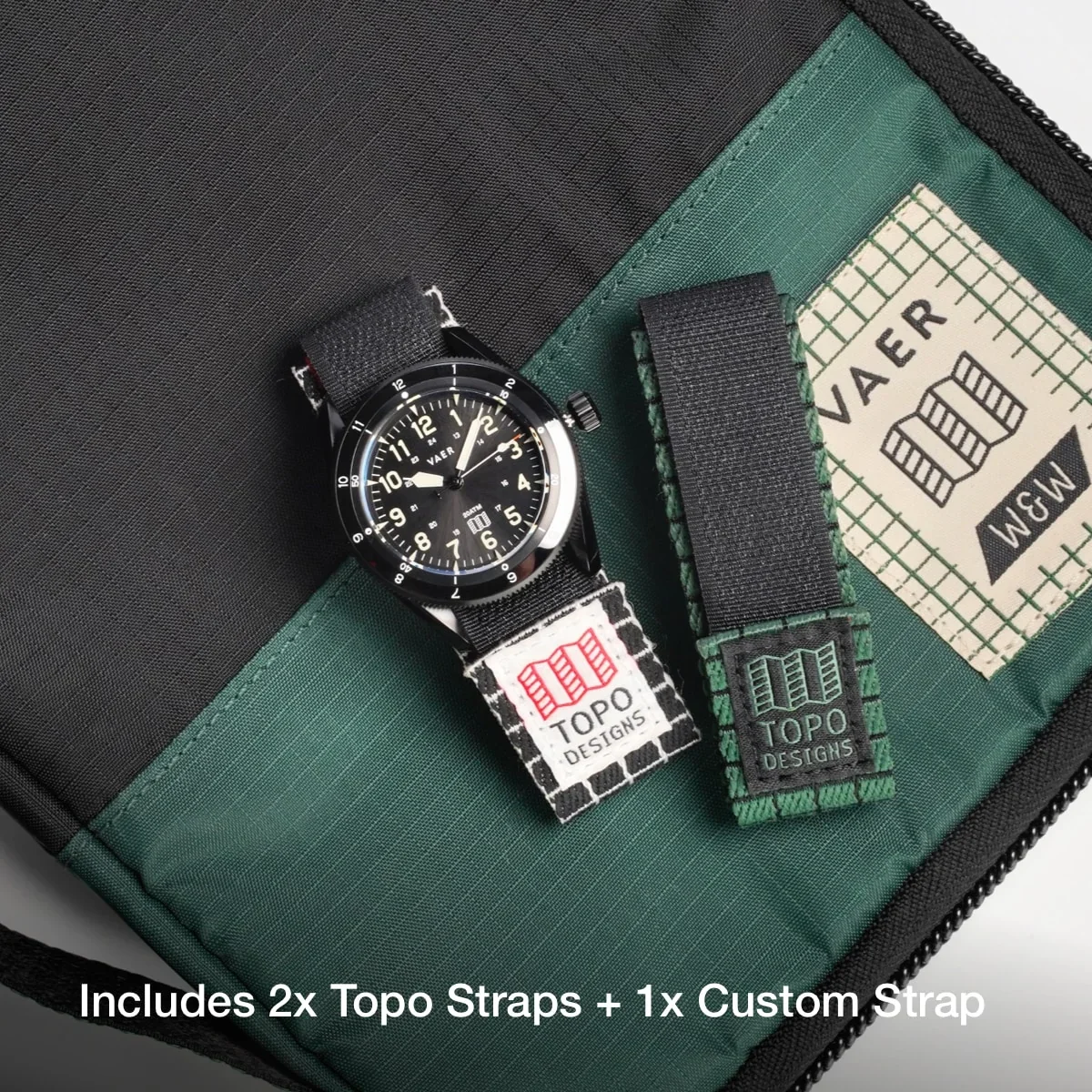 Black Vaer watch on black/white Topo strap, beside black/green Topo strap, on a green/black case with Vaer label.