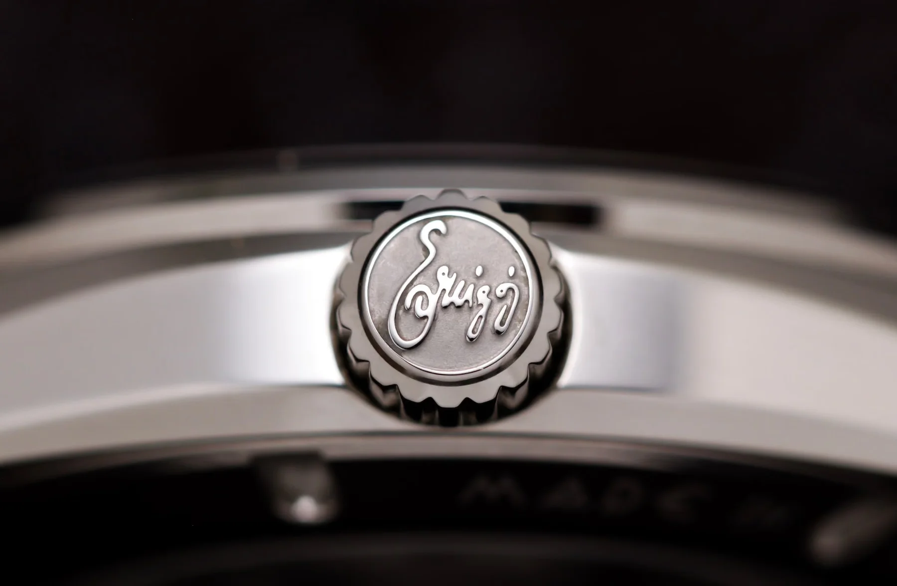 Luxury watch crown with an engraved eruigg logo and fluted edge on polished steel.