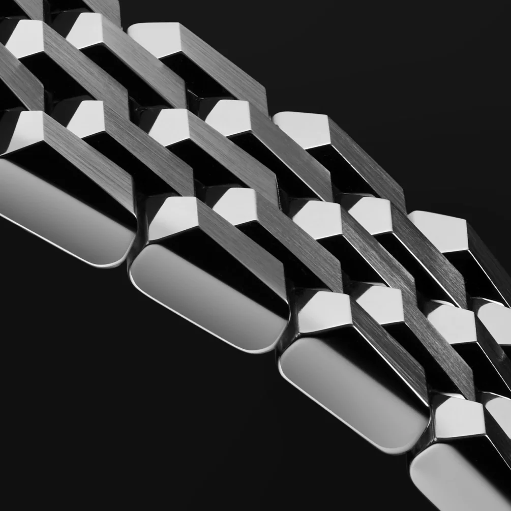 Close-up of a metal watch bracelet with alternating polished and brushed geometric links on a black background.