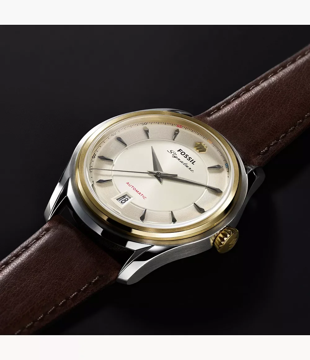 Fossil Signature automatic watch with cream dial, gold bezel, steel case, brown leather strap, date 18, and gold fluted crown.