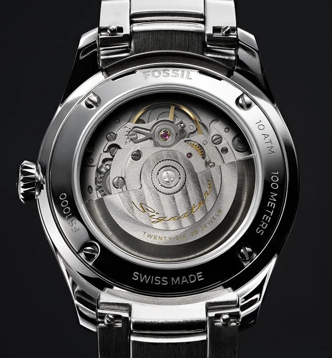 Fossil automatic watch back with exposed Swiss movement, gold Signature rotor, stainless steel case, and bracelet.