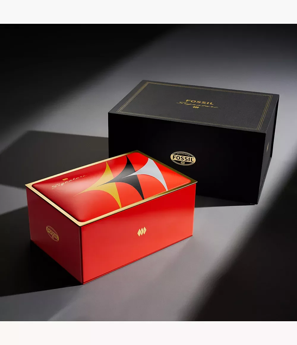 Two Fossil Signature boxes on a dark surface. Black box with gold text, red box with gold trim & colorful starburst lid.