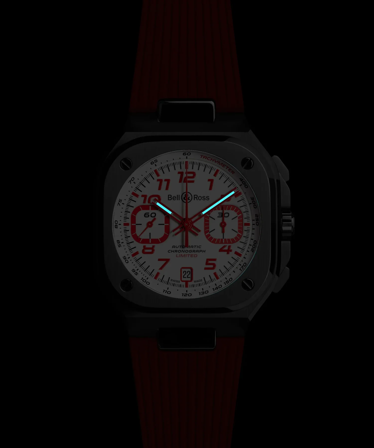 Bell & Ross square chronograph, white dial, red numerals, luminous blue hands, red rubber strap, on black.