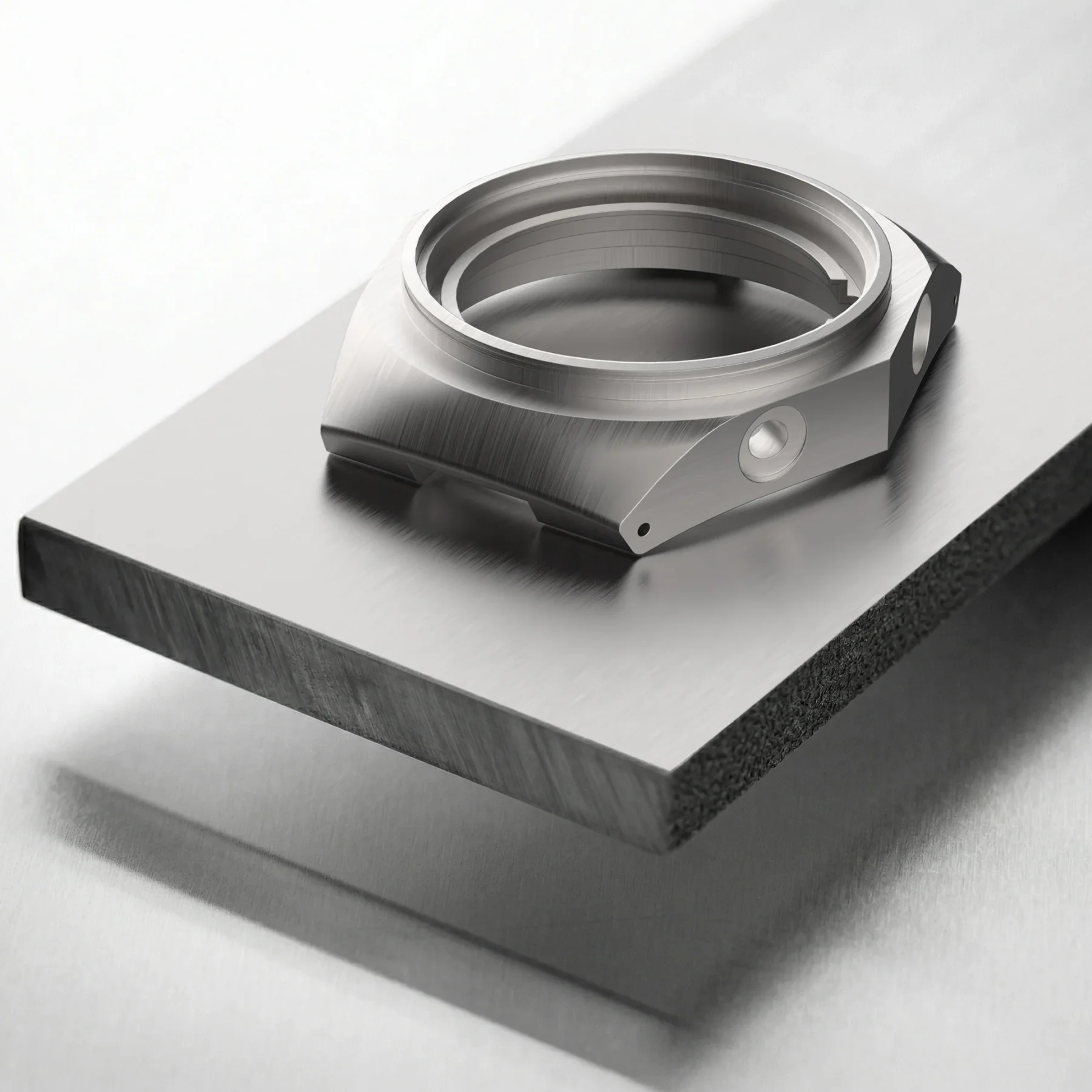 Brushed metal octagonal watch case component on a thick, floating metal slab, emphasizing raw material and precision.