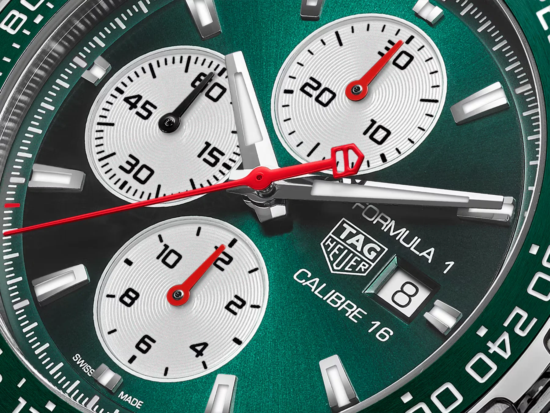 Close-up of brushed green TAG Heuer Formula 1 Chronograph dial with three white subdials, red hands, and date '8'.