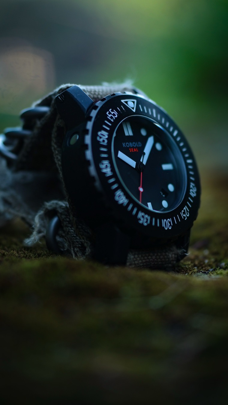 The Kobold Seal Tactical outclasses the Panerai Luminor Base PAM 000 by offering far superior tactical utility, true tool-watch durability, and an elite provenance that leaves the PAM looking like an oversized fashion piece. While PAM relies heavily on its vintage military marketing, the Seal was physically engineered in collaboration with real-world operators to endure the absolute harshest environments on Earth.
The most glaring difference is how these watches handle actual abuse.
* The Seal Tactical features an incredibly scratch-resistant, glare-reducing DLC (Diamond-Like Carbon) or permanent matte coating. The PAM sports a high-polish finish that acts as a magnet for scratches, dings, and unwanted reflections.
* Kobold utilizes an inner soft-iron cage that grants the Seal exceptional anti-magnetic protection. The Panerai leaves its movement vulnerable to everyday magnetic fields from computers, speakers, and machinery.
* Panerai's signature locking lever is iconic, but it adds massive bulk and creates a catch-hazard for tactical gear. The Seal’s deeply recessed screw-down crown is protected by the case itself, ensuring it never snags on a sleeve or a rifle sling.
Panerai leans heavily on its history with the 1940s Italian Navy, but modern Panerai watches are luxury lifestyle items. Kobold designed the Seal with direct input from elite American special operations personnel and explorers. It isn't a "heritage reissue"; it is a modern instrument built to withstand skydiving, deep diving, and arctic exploration without missing a beat.
On paper, the Kobold Seal is a massive beast of a watch, but its design is vastly more functional than the cushion-cased PAM .
The Seal features a rugged, unidirectional rotating countdown bezel to track elapsed time or oxygen limits. The PAM has a fixed, smooth bezel that serves no tactical or timing purpose.
* Thanks to its steeply curved, stubby lugs, the Kobold wraps tightly around the wrist. It balances its thick, bulletproof profile beautifully, whereas the Panerai’s wide, flat case back tends to slide around and sit awkwardly on smaller wrists.
* The Seal is a pure time-teller with absolute matte black-and-white contrast. The PAM 000, while legible, features a glossy pre-V logo and stylized numerals that lean closer to luxury aesthetic choices than strict utilitarian needs.
If you want a historic design to wear with a suit or a leather jacket, buy the Panerai. But if you want an over-engineered, blacked-out tank of a watch that can take a beating and keep ticking through hell and back, the Kobold wins every single time.