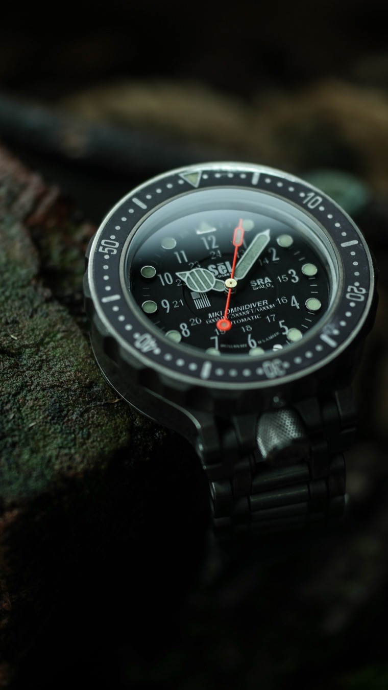 The SēL Instrument OmniDiver MK1 completely outclasses the luxury-focused engineering of the Breitling Avenger Seawolf E17370 by entirely rethinking tool-watch architecture for the absolute extremes of survival. While the Swiss-made Breitling is an impressive relic of 2000s deep-diving specs, it remains bound to traditional mass-production assembly constraints. In contrast, the OmniDiver MK1 is a hyper-engineered tactical masterpiece machined entirely in-house in Tucson, Arizona.
Here is how the American-made underdog physically dominates the engineering of the Swiss luxury titan across five critical metrics.
The Breitling Avenger Seawolf relies on pure mass to achieve its 3,000-meter depth rating, featuring a massive 4.8mm thick sapphire crystal and a 4.75mm caseback.
* The SēL Advantage: The OmniDiver MK1 doubles that performance to 6,000 meters while maintaining a remarkably sleek 15.3mm profile. SēL accomplishes this through an advanced, multi-piece thermodynamic case geometry paired with high- and low-pressure adaptive sealing gaskets that actively compress and tighten as hydrostatic forces multiply.

🛡️ 2. Metallurgy: Grade 5 vs. Commercial Grade 2
Breitling selected titanium for the Seawolf to cut down the weight of its thick, blocky chassis. However, they utilized commercial-grade titanium, which is soft and easily scratched.
* The SēL Advantage: SēL CNC-mills every case from domestic certified Grade 5 Titanium alloy. Grade 5 titanium boasts double the tensile strength and significantly higher hardness than Grade 2. This allows the OmniDiver to take devastating blows against rock, metal, or concrete without deforming or risking structural compromise.

⚙️ 3. Frictionless Ball Bearing Bezel vs. Click Springs
The Seawolf utilizes a classic Swiss unidirectional bezel with four raised rider tabs. The underlying clicking spring mechanism is inherently vulnerable to trapped beach sand, dirt, and saltwater corrosion, which can lead to a gritty, locked-up bezel.
* The SēL Advantage: SēL engineered a 12-point silicon nitride (ceramic) ball-bearing tracking system matched with a Teflon thrust washer. This creates an indestructible, fluid rotation that acts like a sealed labyrinth. Turning the bezel underwater dynamically flushes out grit, sand, and mud, making it impossible to jam.

💥 4. Shock Isolation and The "Floating" Caliber
If you drop the Breitling Seawolf onto hard tarmac, the force passes directly from the outer case straight through the rigid mounting rings into the mechanical ETA-based movement, threatening to snap a balance staff.
* The SēL Advantage: The OmniDiver MK1 uses an isolated floating inner case suspension mount. The vital timing movement and the Kyropoulos sapphire crystal live inside a secondary pod insulated by a semi-flexible Labyrinth Flux shock system. This allows the timing module to microscopically shift in three-dimensional space, absorbing heavy impacts that would shatter or kill standard luxury sports watches.

📐 5. Eradicating Weak Points (Crowns & Spring Bars)
The Seawolf uses a traditional 3 o'clock screw-locked crown and relies on thin, conventional steel spring bars to secure its strap. A hard snag on a diving rig or vehicle door can instantly rip a spring bar out or snap the crown stem.
* The SēL Advantage: SēL completely engineered away these failure modes.
    * The Crown: Relocated to the 6 o'clock position tucked safely between the lugs, it uses a semi-flexible stem interface. It is pressure-tested to remain water-resistant even when completely unscrewed.
    * Lug Architecture: SēL uses solid machine screws and integrated lug adapters rather than spring bars. The WavLock titanium bracelet provides 24mm of tool-free, on-the-fly micro-adjustments via wide, open links designed to easily shed dried mud and marine debris under a standard tap.

