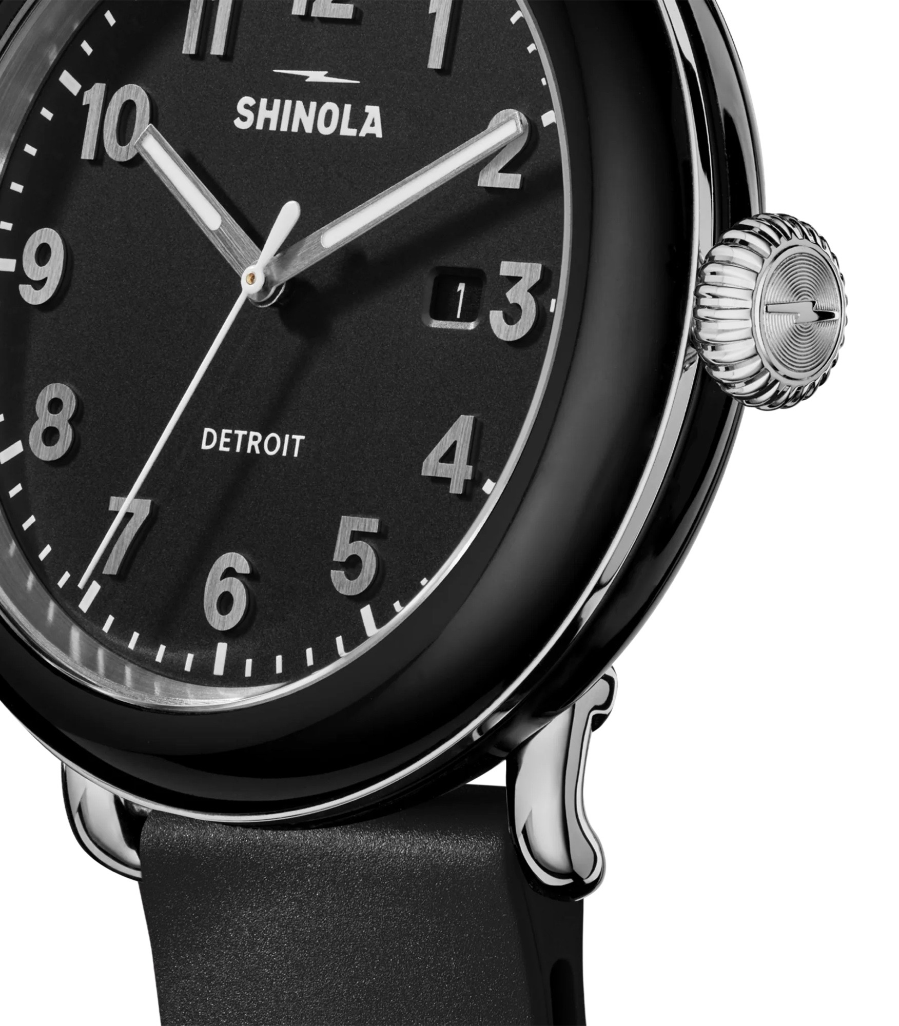 Close-up of a black Shinola Detrola watch. Black dial, silver numerals, white hands, date "13", silver textured crown, black strap.