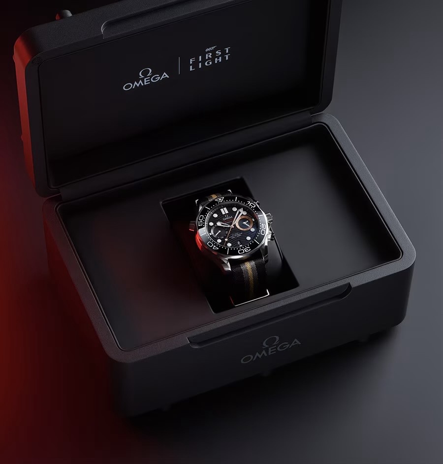 Omega 007 First Light Seamaster on NATO strap in open black box. Omega & 007 logos on lid. Dark, red-lit setting.